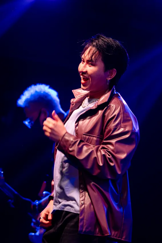 Singer in a brown jacket performing into a microphone at Paragon Club, Cheras