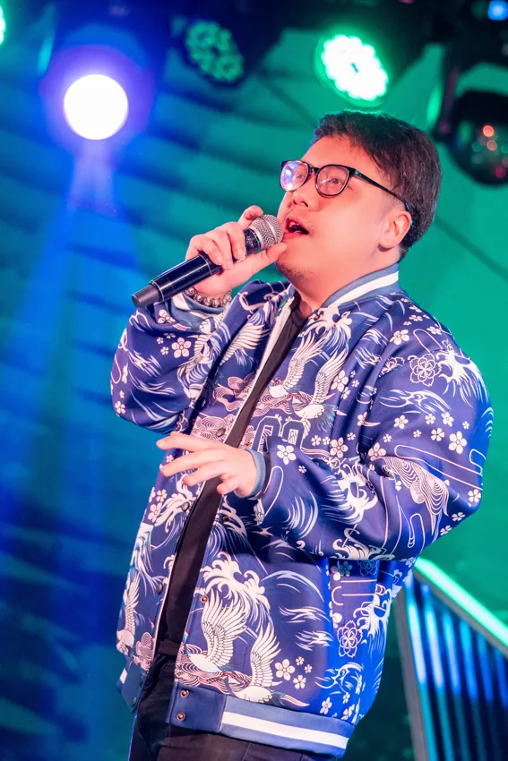 Male vocalist in a blue patterned jacket under green lights at Paragon Club, Cheras