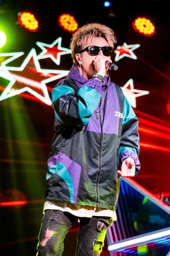 Vocalist wearing sunglasses in front of bright star graphics at Paragon Club, Cheras