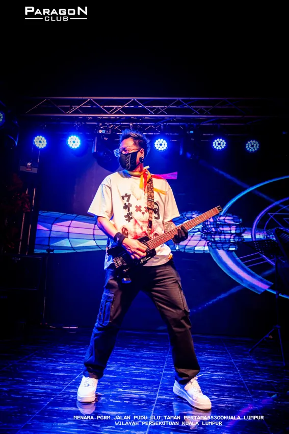 Guitarist standing beneath blue stage spotlights at Paragon Club, Cheras