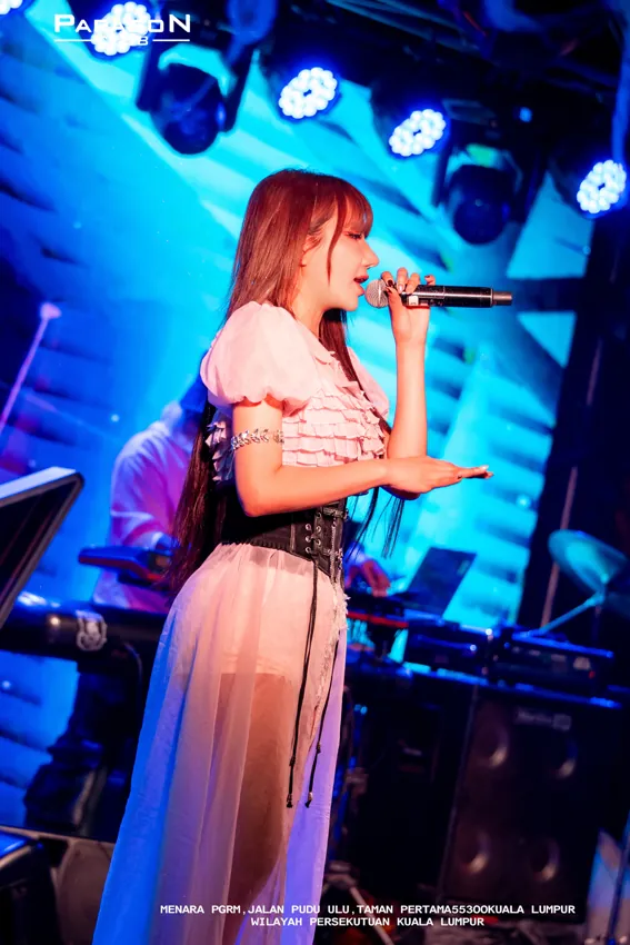 Singer in a pale dress performing under blue lights at Paragon Club, Cheras