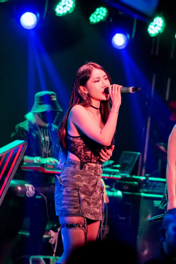 Vocalist holding a microphone under green and blue lights at Paragon Club, Cheras